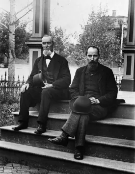 1890s 1900 Two Bearded Men In Suits Holding Bowler Hats Sitting On Stairs In Front Of House